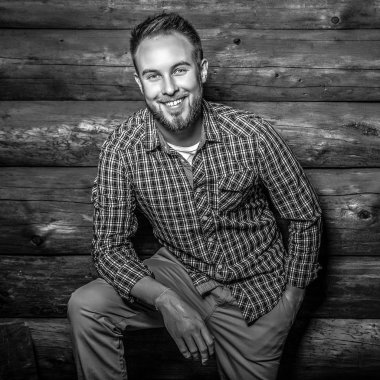 Zarif yakışıklı genç poz ahşap arka plan karşı. Siyah-beyaz fotoğraf.