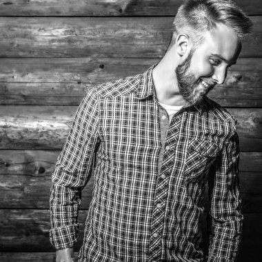 Zarif yakışıklı genç poz ahşap arka plan karşı. Siyah-beyaz fotoğraf.