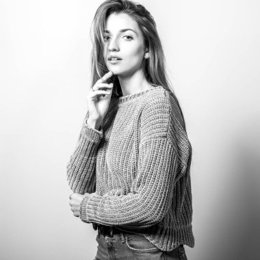 Kazak içinde genç model kadın stüdyoda poz. Siyah-beyaz fotoğraf.