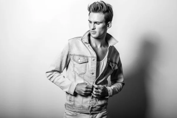 Handsome young man in jeans jacket. Black-white studio portrait.