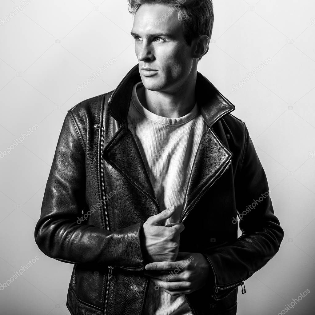 Handsome young man in classic leather jacket. Black-white studio portrait.