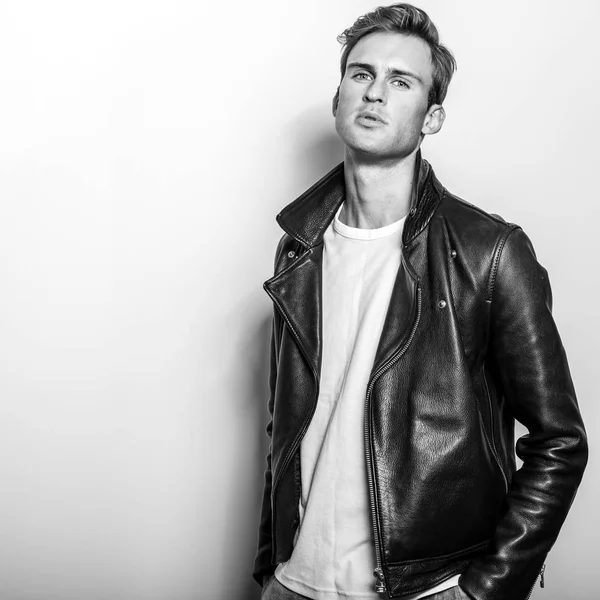 Handsome young man in classic leather jacket. Black-white studio portrait.