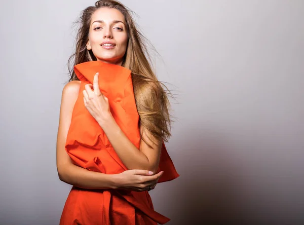 年轻模特女人在橙色礼服姿势在工作室 — 图库照片