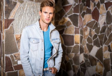 Doğal taş arka plan karşı genç yakışıklı erkek modeli.