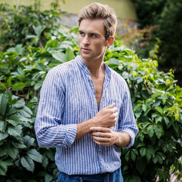 カジュアルな服を着た若いハンサムな男が夏の庭でポーズをとる — ストック写真