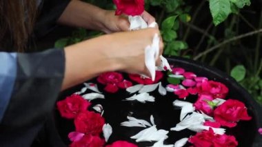 Su kabında kadın elleri ve çiçek yaprakları. Tam HD Görüntü.