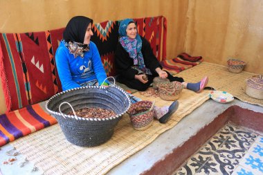 Marrakesh, Morocco - 2016-03-02 : Ladies working to grind argan nuts to make oil, butters and other products, near Marrakesh, Morocco, Africa clipart