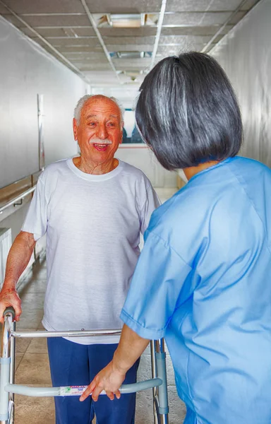 Nurse assisting elder people in a rehab facility gym.