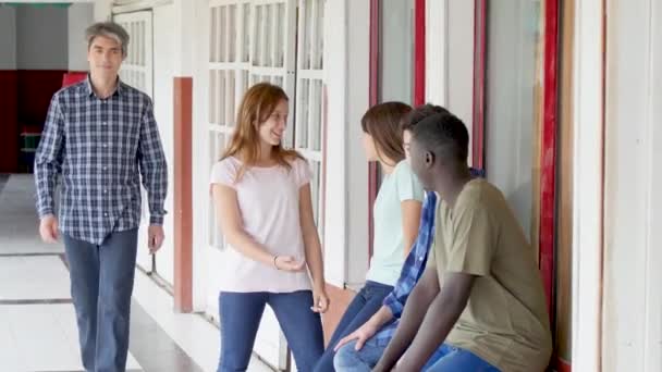 Gruppe Fröhlicher Teenager Unterhält Sich Auf Schulflur Und Lehrer Kommt — Stockvideo