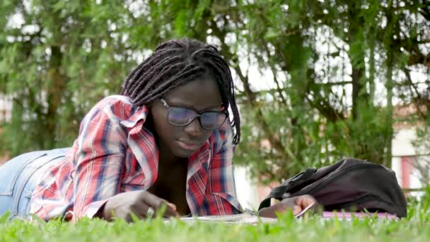 美国黑人女青年躺在草地上看书 — 图库视频影像