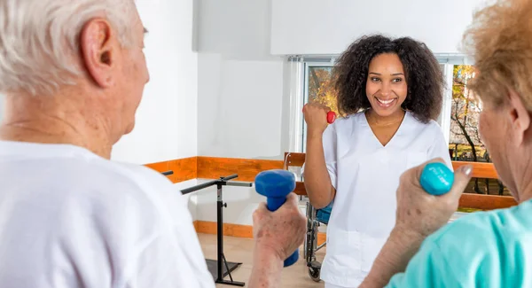 Afroamerican 护士帮助老年公民在医院健身房举重 — 图库照片
