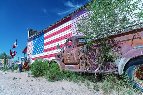SELIGMAN, AZ - JUNE 29, 2018: Old truck and american flag along Route 66. This is the most famous historic route in the US.