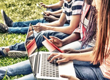 Dizüstü bilgisayarlar ve akıllı telefonlar açık kullanarak karışık ırklar genç grup.
