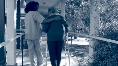 yaşlı bayan hasta parkta yürümeye yardımcı hemşire