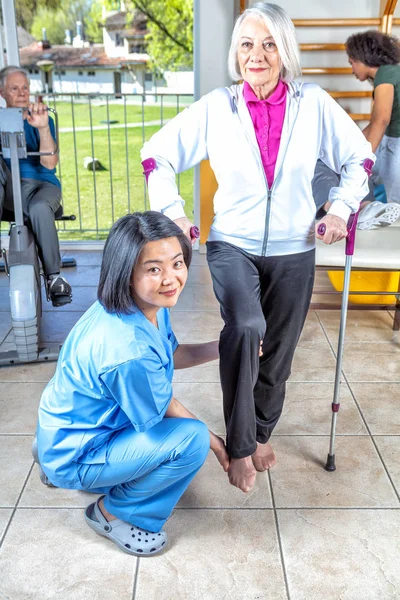 Rehab facility for elder people. Gym with man, woman and teachers.