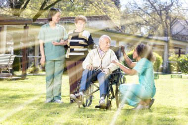 İki kadın doktorlar yaşlı erkek ve kadın ile fiziksel sakatlık ih rehabilitasyon tesis Bahçe yardım.