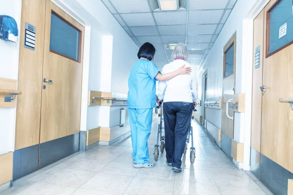 病院の廊下での歩行で老婆を助けるアジア医師 — ストック写真