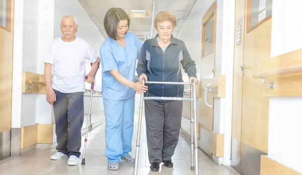 亚洲医生帮助老年妇女与沃克和男子在医院过道 — 图库照片