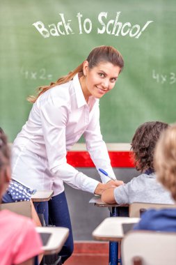 Kadın öğretmen okula birincil sınıf, geri mutlu kara tahta işaret.