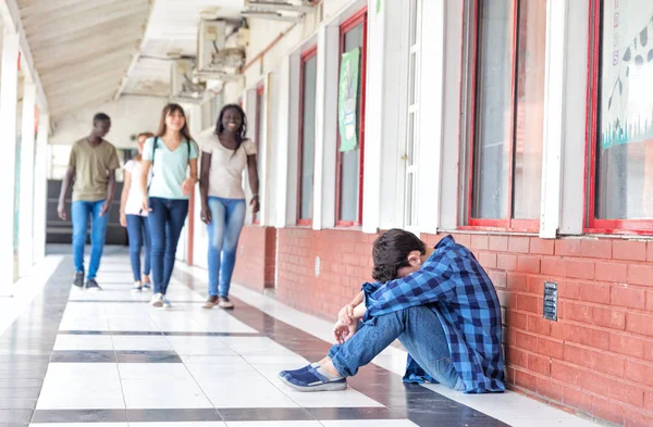 Acoso escolar. Muchacha trastornada en el pasillo mientras sus compañeros de broma h — Foto de Stock