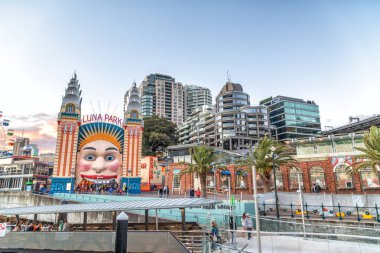 SYDNEY, AUSTRALIA - AUGUST 18, 2018: City skyscrapers and Luna Park. Sydney attracts 15 million tourists annually. clipart