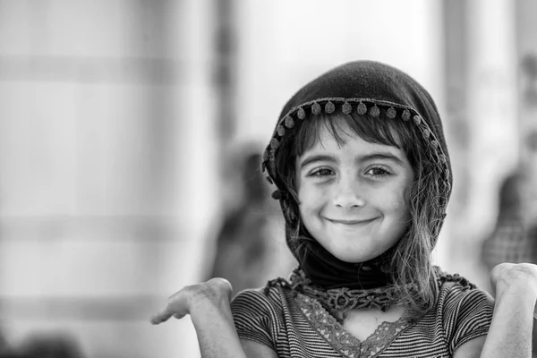 Portrait of young smiling muslim girl in the adras hijab headscarf or shawl visiting a mosque.