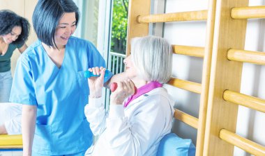 Yaşlı kadın küçük ağırlık içinde rehabilitasyon dacility, öğretmenler tarafından yardım ile.