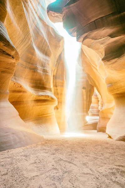 Beam of sand is flowing off the rocks in the interior of the narrow walls of the winding Antelope Canyon, Arizona.