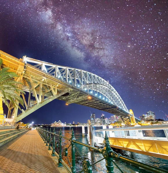 Night view of Sydney Harbor Bridge with stars and milky way, Australia.