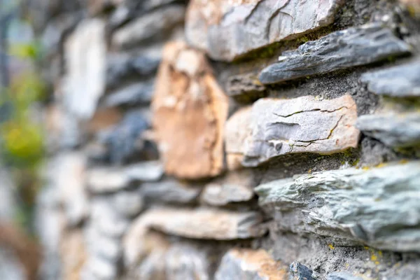 Street wall with protruding rocks, blurred background