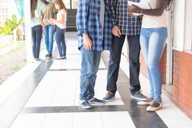 Öğretmen ve öğrenciler okul koridorda konuşmaya grupları.