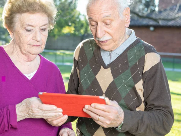 Mutlu Yaşlı Çift Okuma Tablet Bahçe Önden Görünümü — Stok fotoğraf