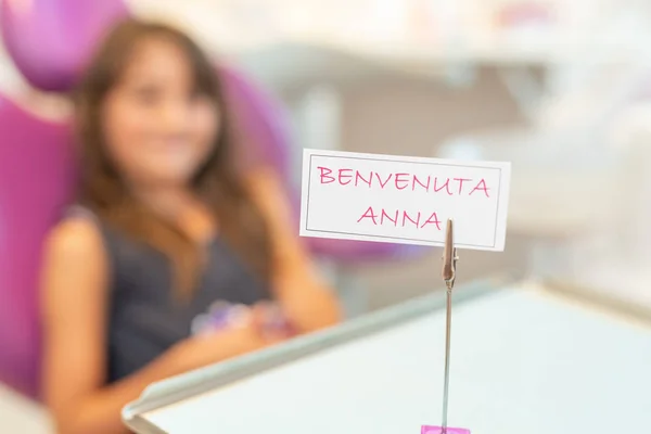 Welcome sign in dentist room for children, blurred girl in background