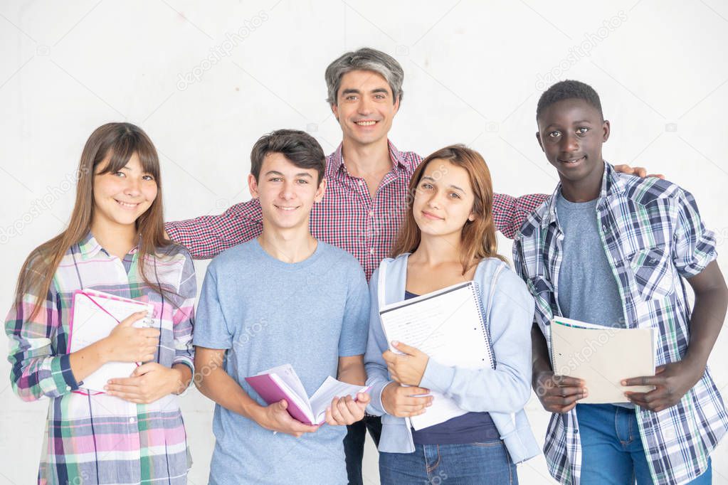 Teacher at school embracing multi ethnic students, isolated on white wall.