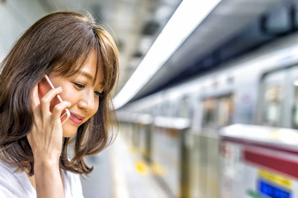 Hermosa Chica Asiática Sonríe Hablando Teléfono Celular Mientras Espera Metro — Foto de Stock