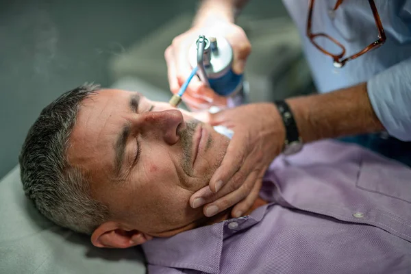 50年代白种人在美容诊所接受激光面部治疗的近拍 接受局部冷冻治疗的男性 — 图库照片