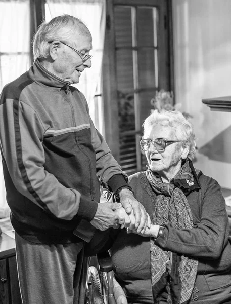 笑着的老两口 夫妻坐在轮椅上 温柔地牵着手 — 图库照片