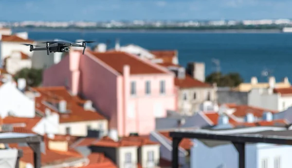 Drone flying above city buildings on a sunny day.