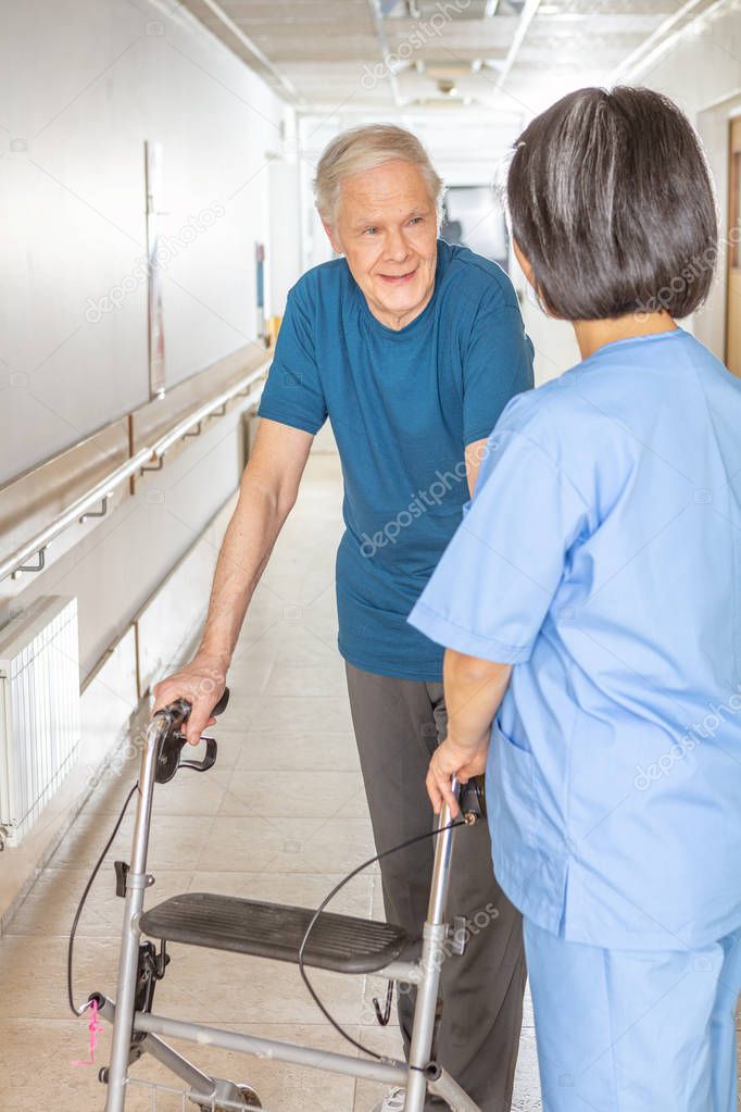 Elderly patient with walker is smiling at the nurse.