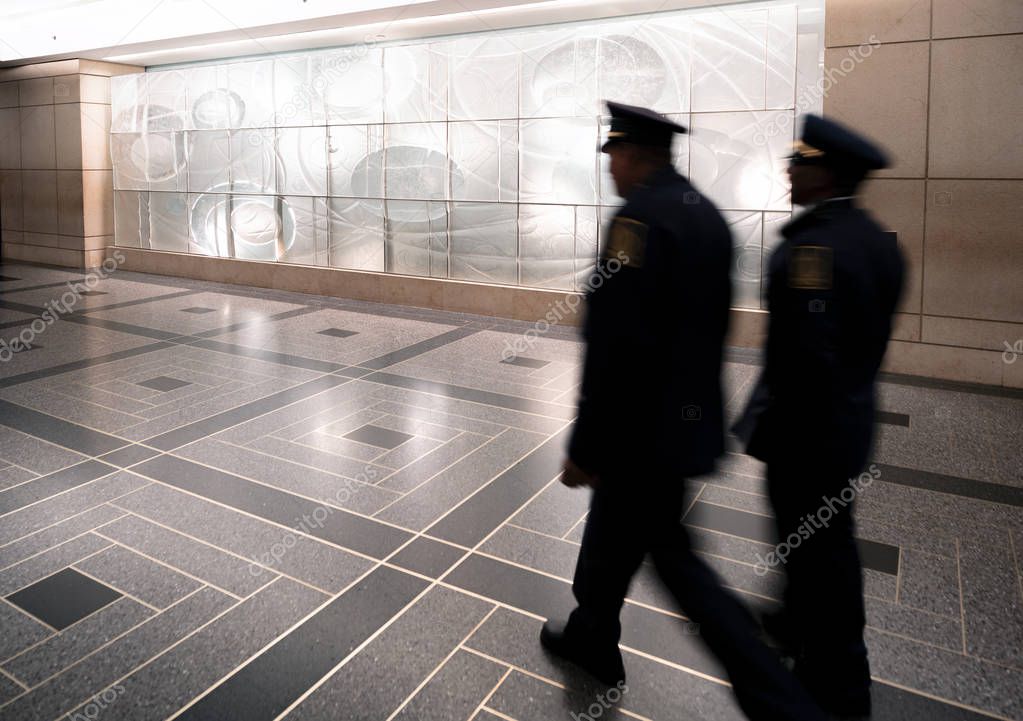 Police officers walking inside main station, blurred view