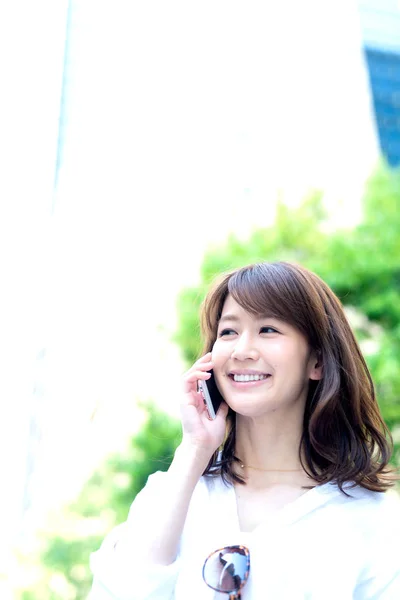 Beautiful business woman calling by phone in the city center.