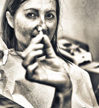 Diş muayenehanesinde oturan güzel bayan diş implantını gülümserken gösteriyor..