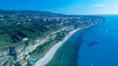 Tropea silueti ve İtalya 'nın sahil şemsiyeli kıyı şeridi. Güzel güneşli bir sabahta hava manzarası.