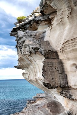 Bulutlu bir günde okyanusta yukarıda güzel dev kaya.