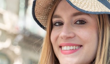 Şehirde gülümseyen hasır şapkalı mutlu kız.