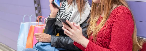 Κορίτσια Σακούλες Δώρων Χρησιμοποιώντας Smartphones Κάθονται Ένα Παγκάκι Σταθμό Του — Φωτογραφία Αρχείου