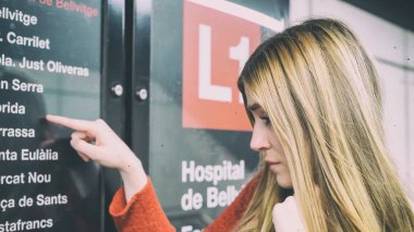 Bir metro istasyonunda metro haritası isteyen genç kız.