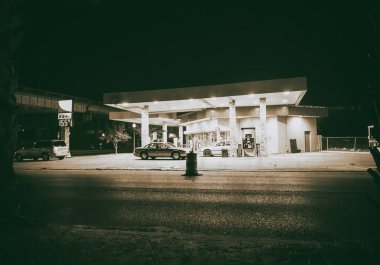 Yolun karşı tarafına gelen geceleri benzin istasyonu dış görünümü.