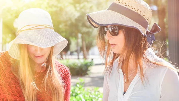 Ein paar Mädchen lächeln im Freien und schauen sich etwas an — Stockfoto