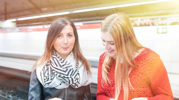 笑みを浮かべて、地下鉄駅で話している女性の友人のカップル — ストック写真